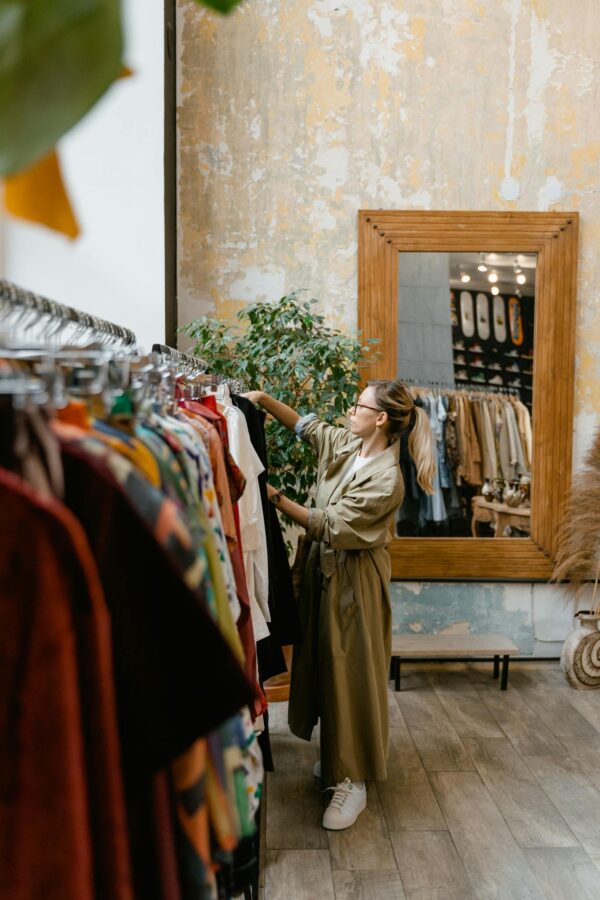 A stylish woman browsing clothes in a trendy boutique with wooden decor.