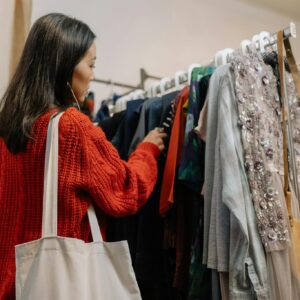 A woman browses a clothing rack in a cozy thrift shop, selecting garments.