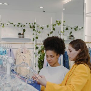 Two women shopping for clothes in a modern boutique, guided by a personal stylist.