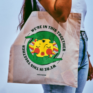 Woman carrying tote bag with colorful 'We're in this Together' artwork.