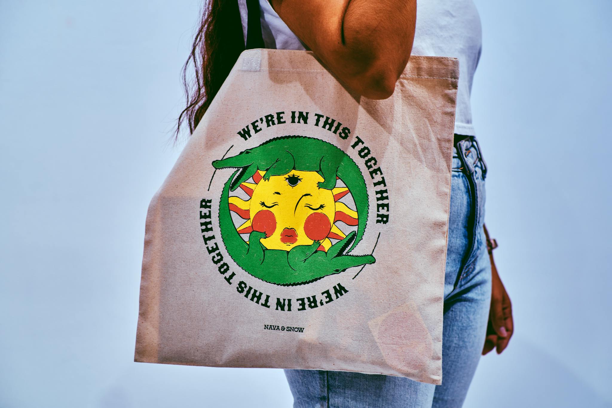 Woman carrying tote bag with colorful 'We're in this Together' artwork.